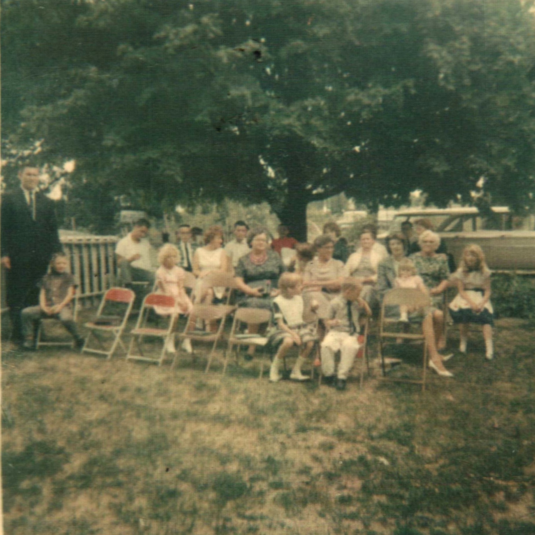 People gathered for church service outside and sitting on folding chairs